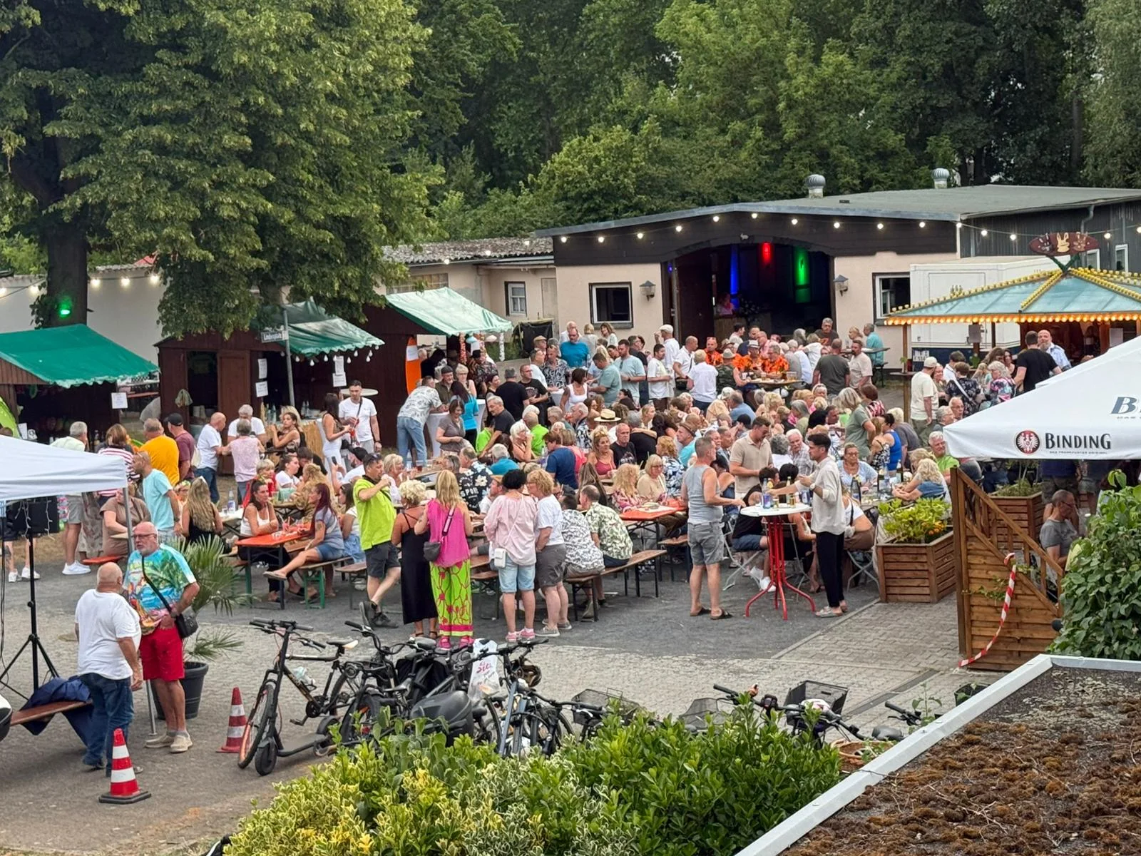 Gäste sitzen beim Sommerfest an langen Tischen auf dem Vereinsgelände